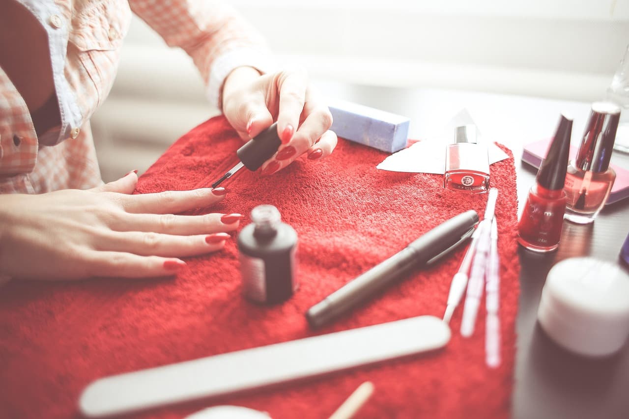 A manicure in progress on a red towel, with polishes and tools